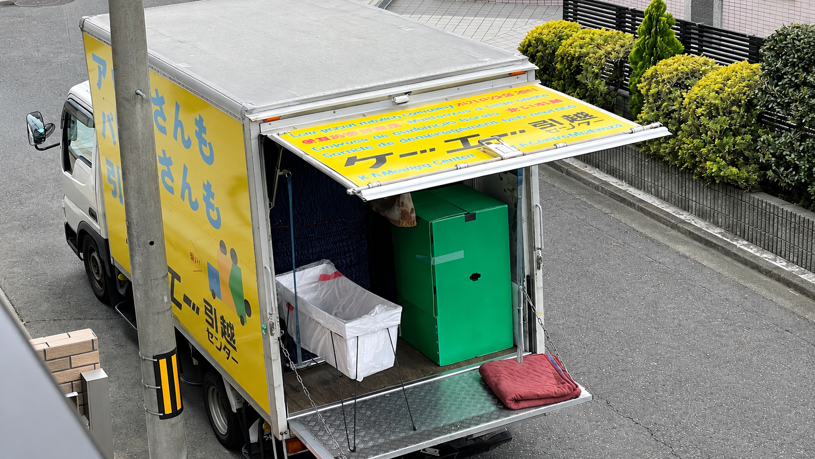 Moving truck with an open cargo compartment and packed belongings on a residential street in Japan.
